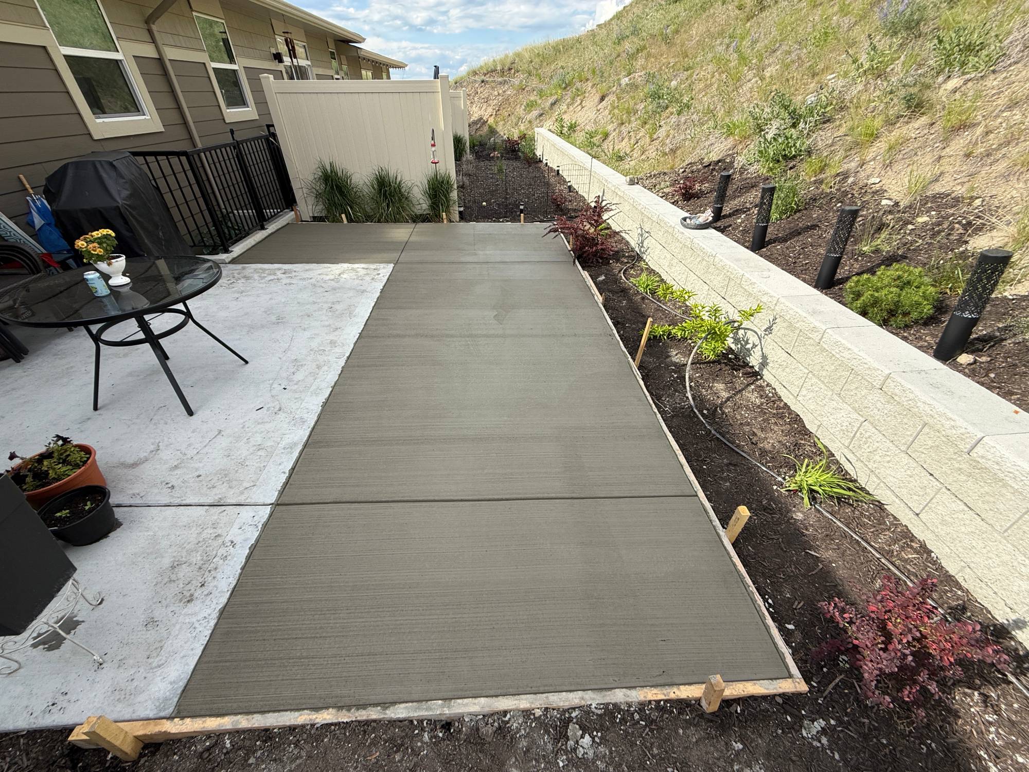 Freshly poured concrete patio with garden.