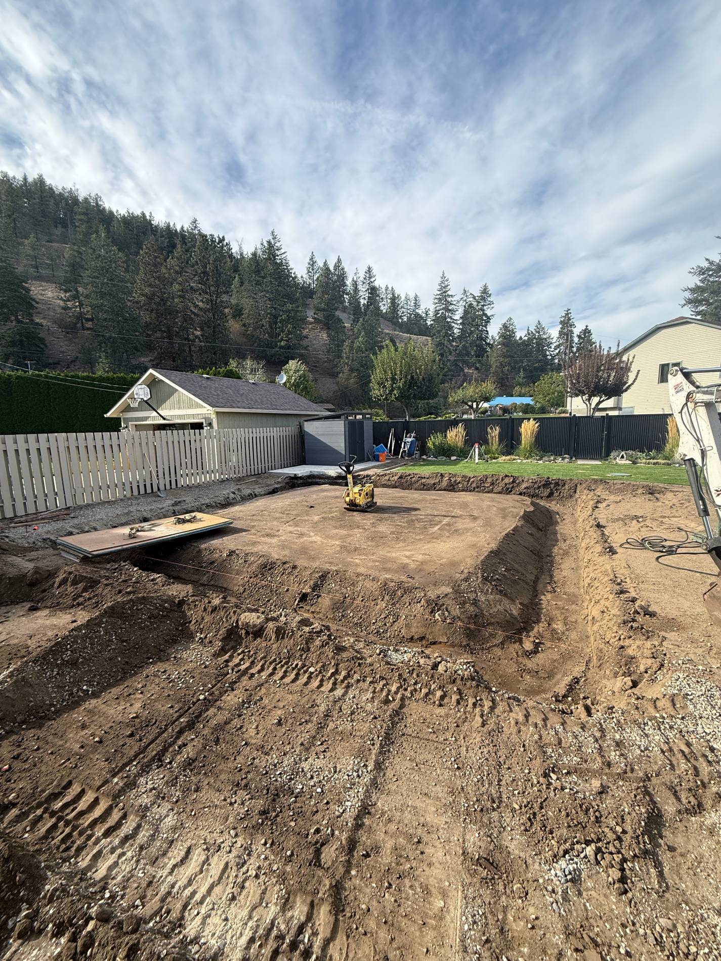 Backyard excavation with dirt and machinery.