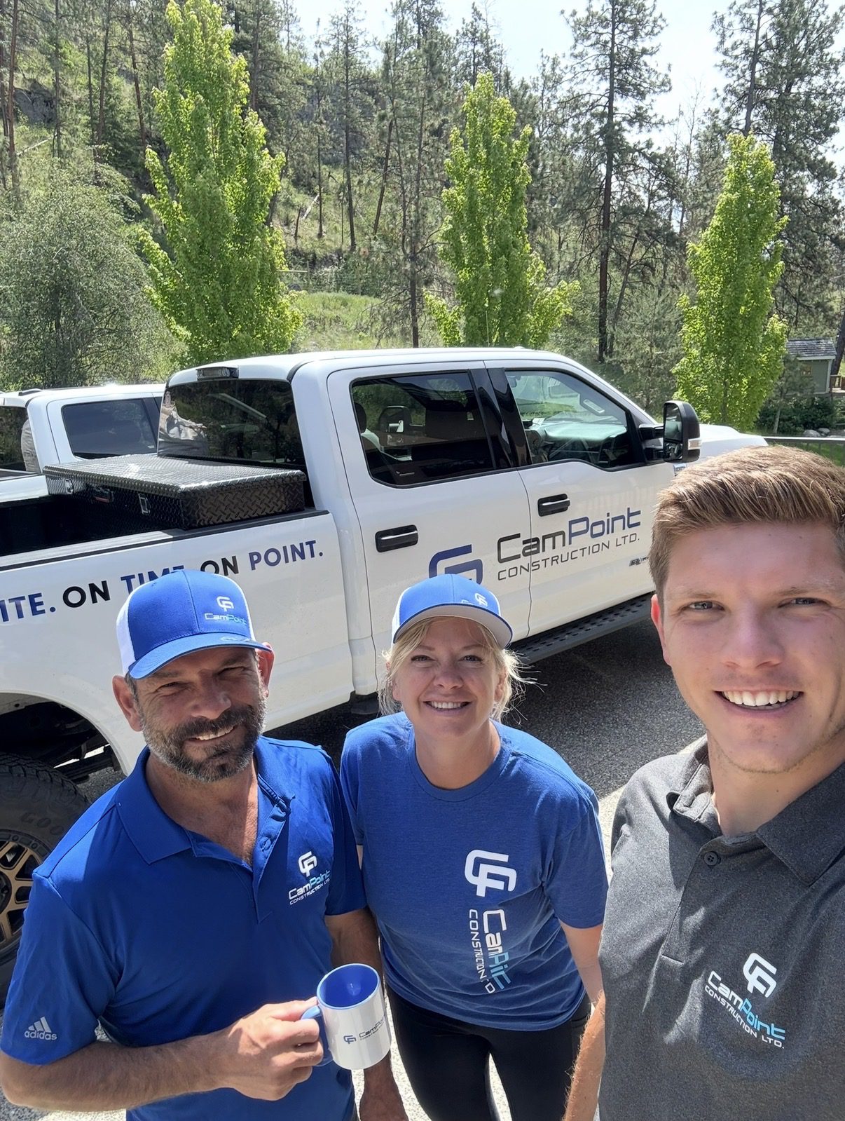 Three people smiling near company truck.