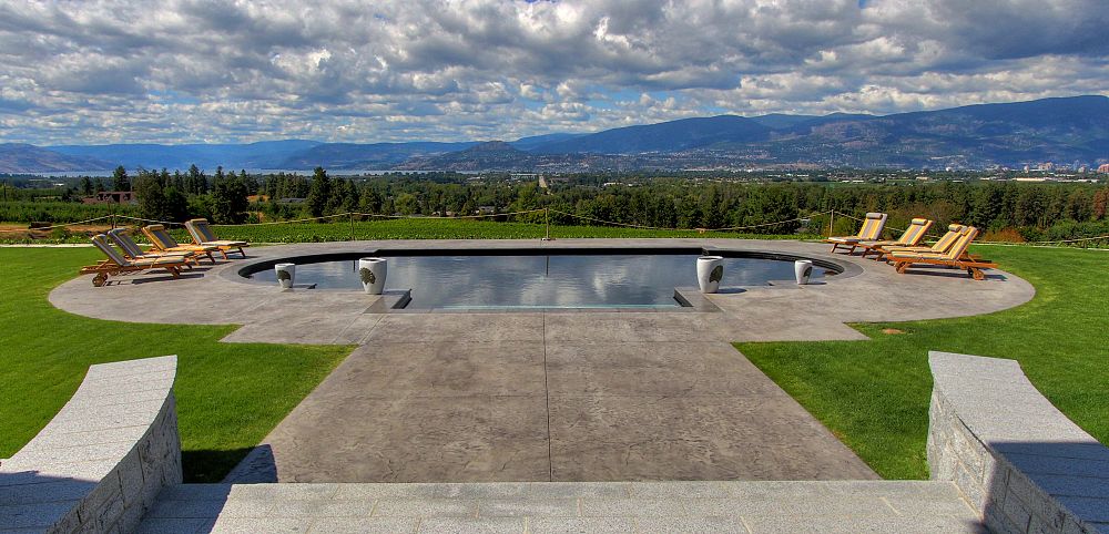 Infinity pool with loungers overlooking scenic landscape.