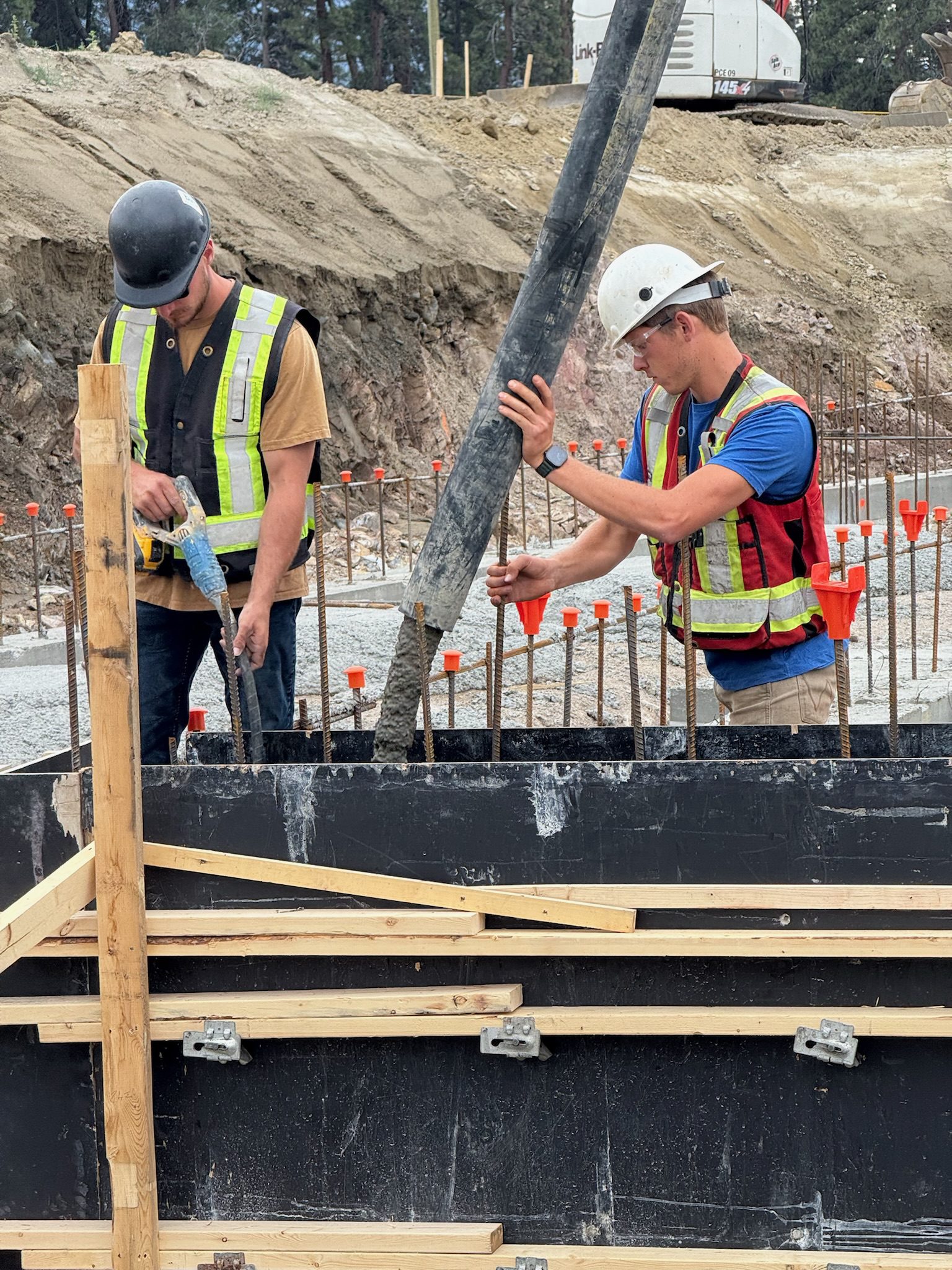 Construction workers pouring concrete into formwork.